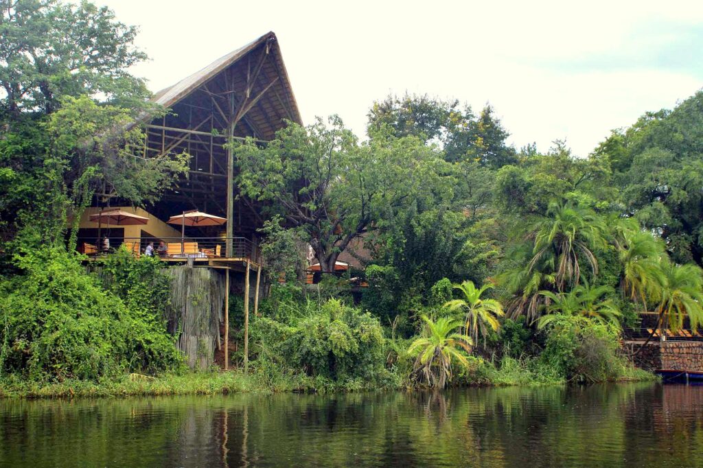Riverfront view of Chobe Safari Lodge in Botswana, surrounded by lush greenery on the banks of the Chobe River near Chobe National Park.