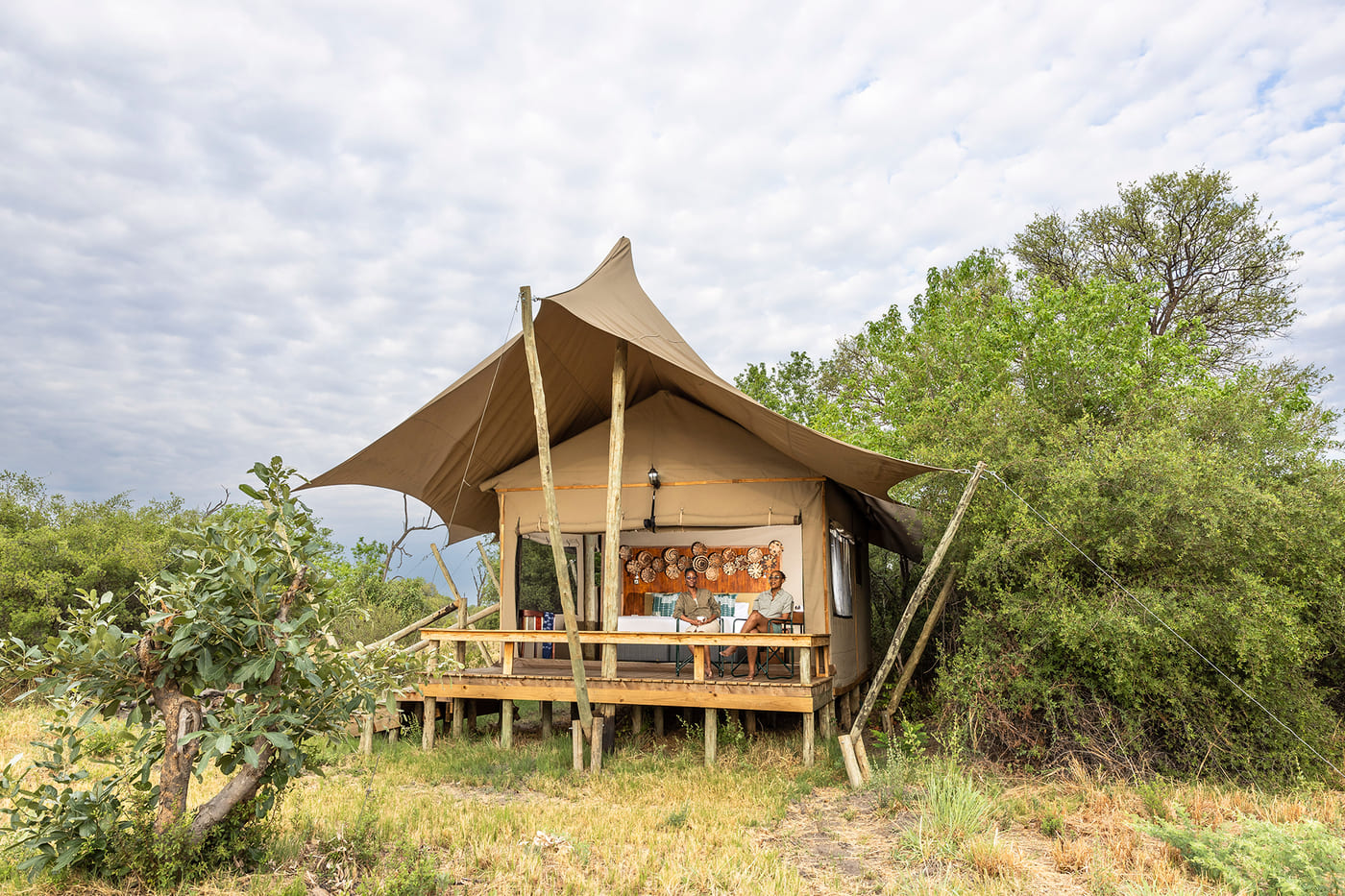Canvas tent at Camp Khwai raised on a wooden platform with private deck and bush surroundings.