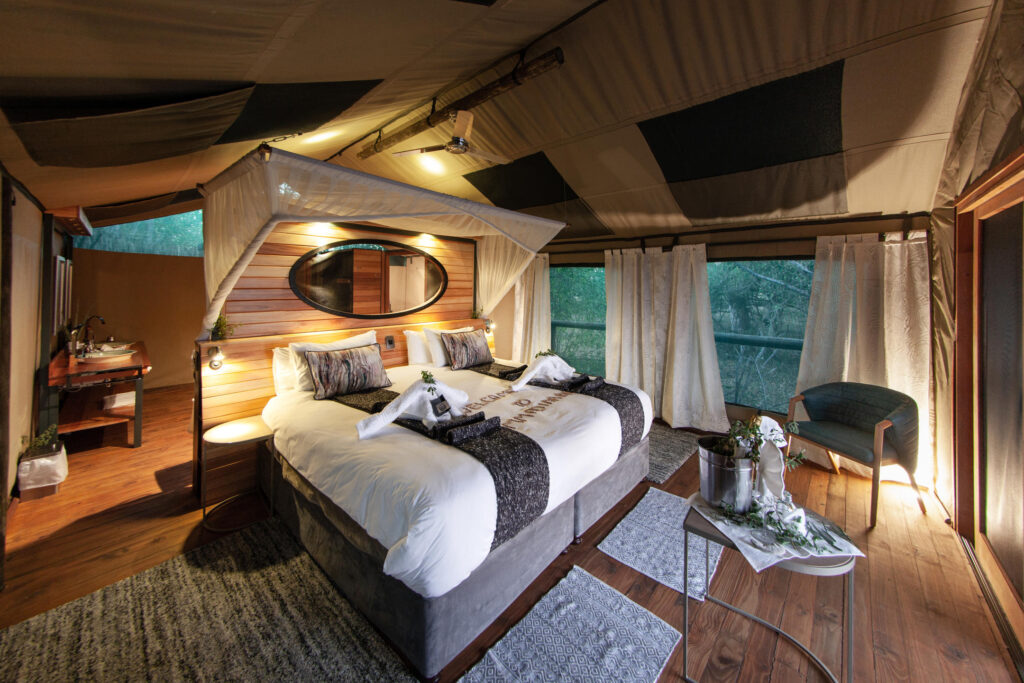 Luxury tented suite at Mma Dinare Camp with king bed, natural wood accents and private deck overlooking the river in the Okavango Delta.