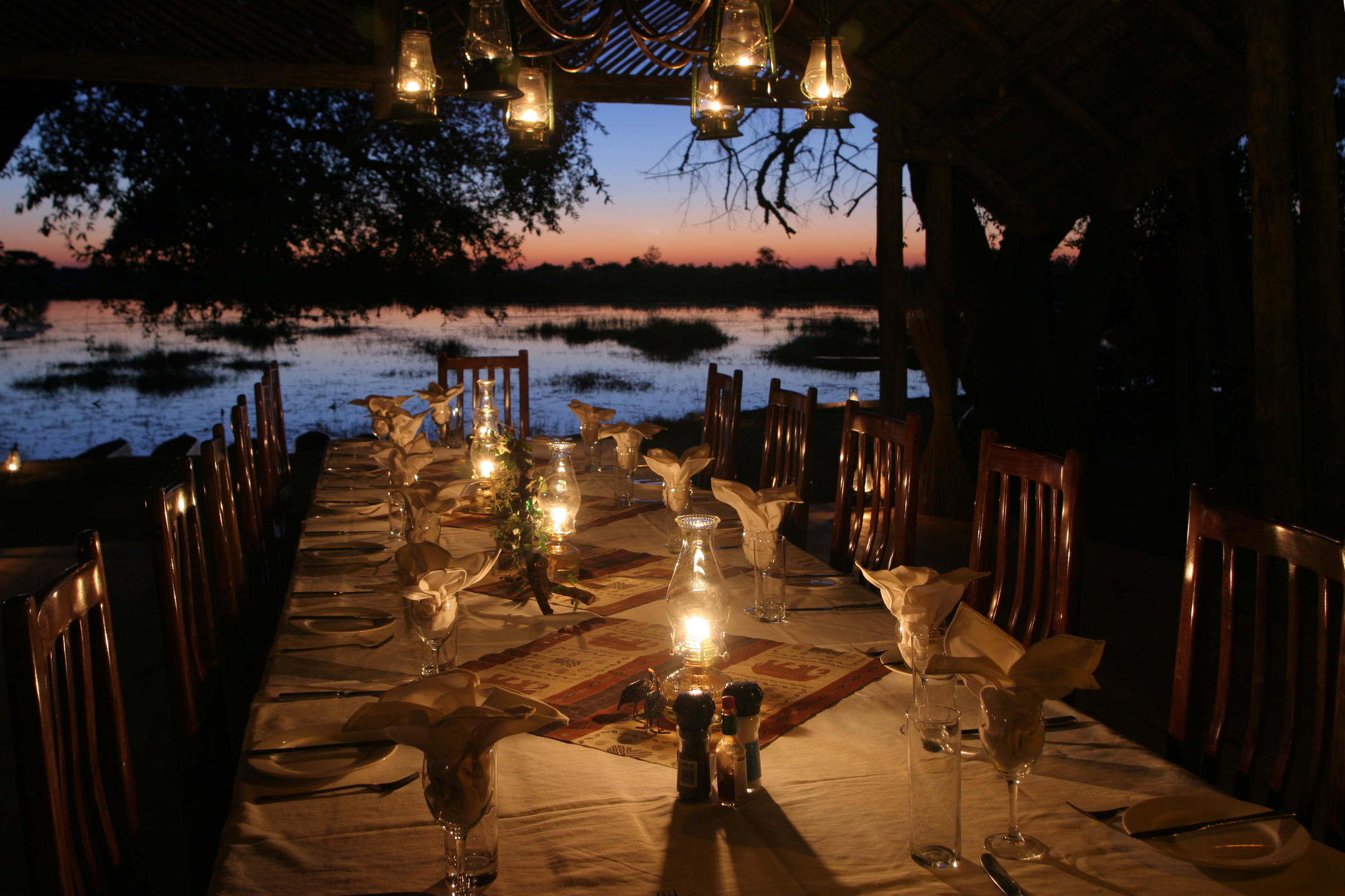 Candle-lit dinner setup overlooking the lagoon at sunset at Pom Pom Camp in the Okavango Delta.