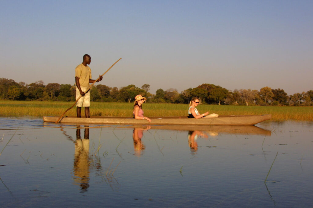 Guests enjoying a traditional mokoro boat excursion on calm waters at Pom Pom Camp.