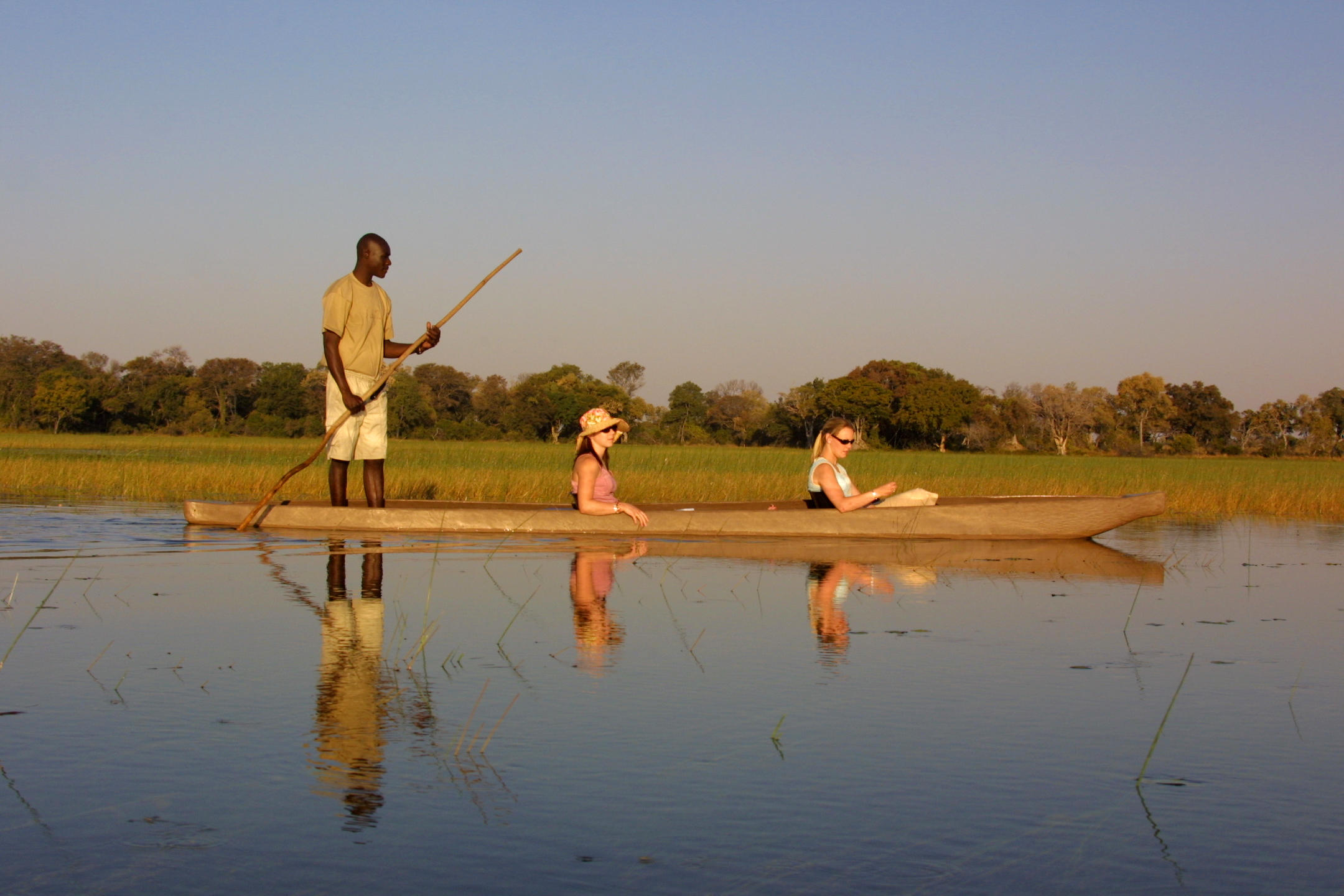 Guests enjoying a traditional mokoro boat excursion on calm waters at Pom Pom Camp.