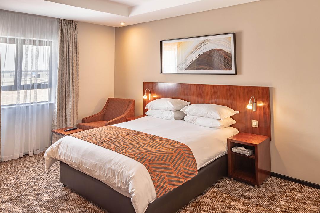 Comfortable guest room at City Lodge Hotel O.R. Tambo Airport with a double bed, work desk, and modern amenities for overnight stays.
